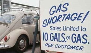 A Volkswagen Beetle in front of a sign that reads, "Gas shortage, sales limited to 10 gallons of gas per customer."